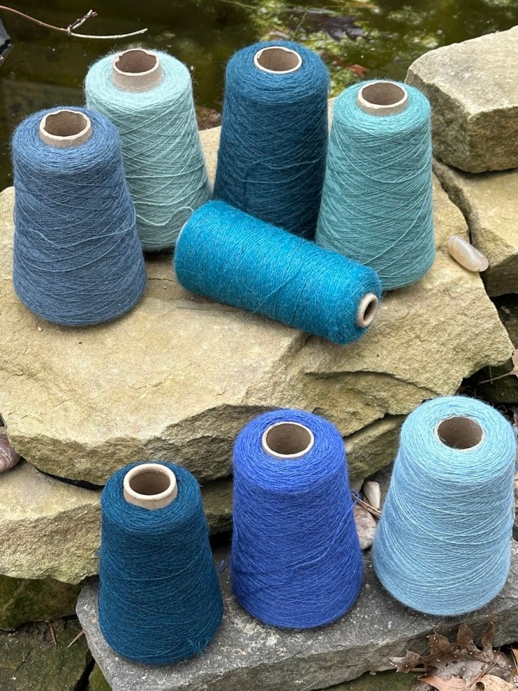 Cones of weaving yarn in various shades of blue